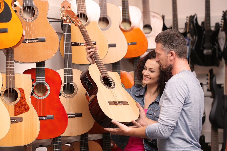 Man and woman choosing guitar in store
