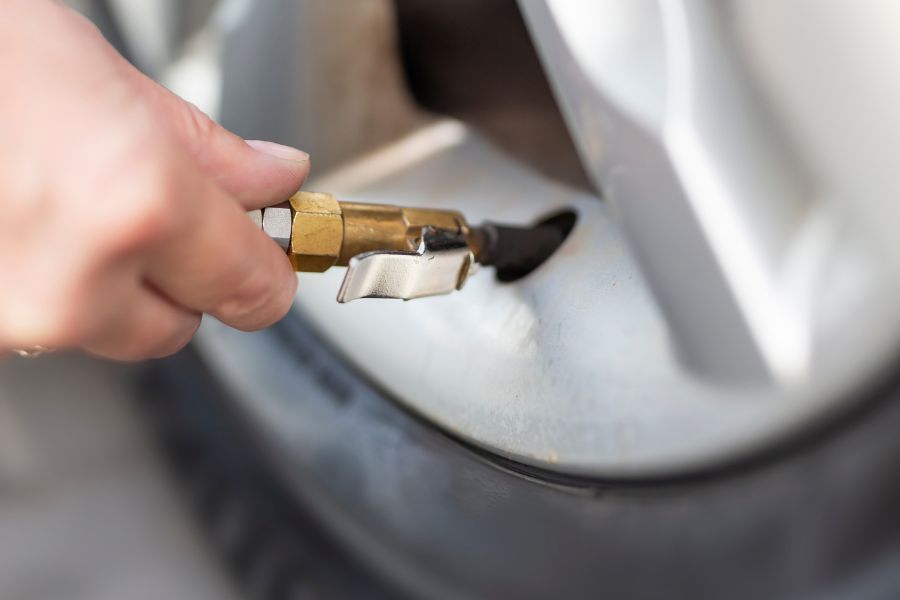 Man controlling tire pressure of his car tire