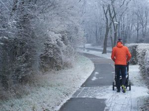 man walking with a stroller wearing winter jacket